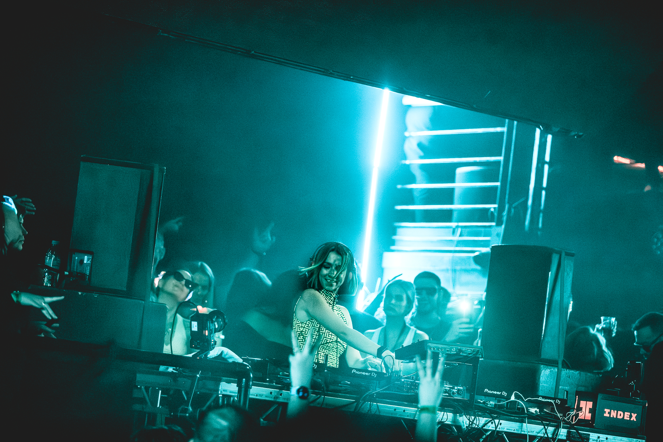 dark room with a lot of people and some neon lights in the back, dj miss Monique playing her set