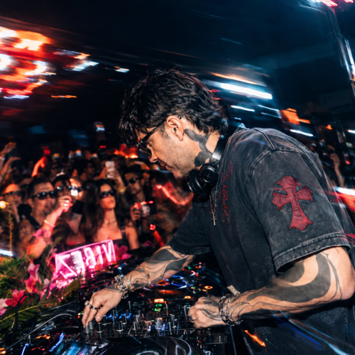 A DJ mixing at the decks in front of a packed crowd